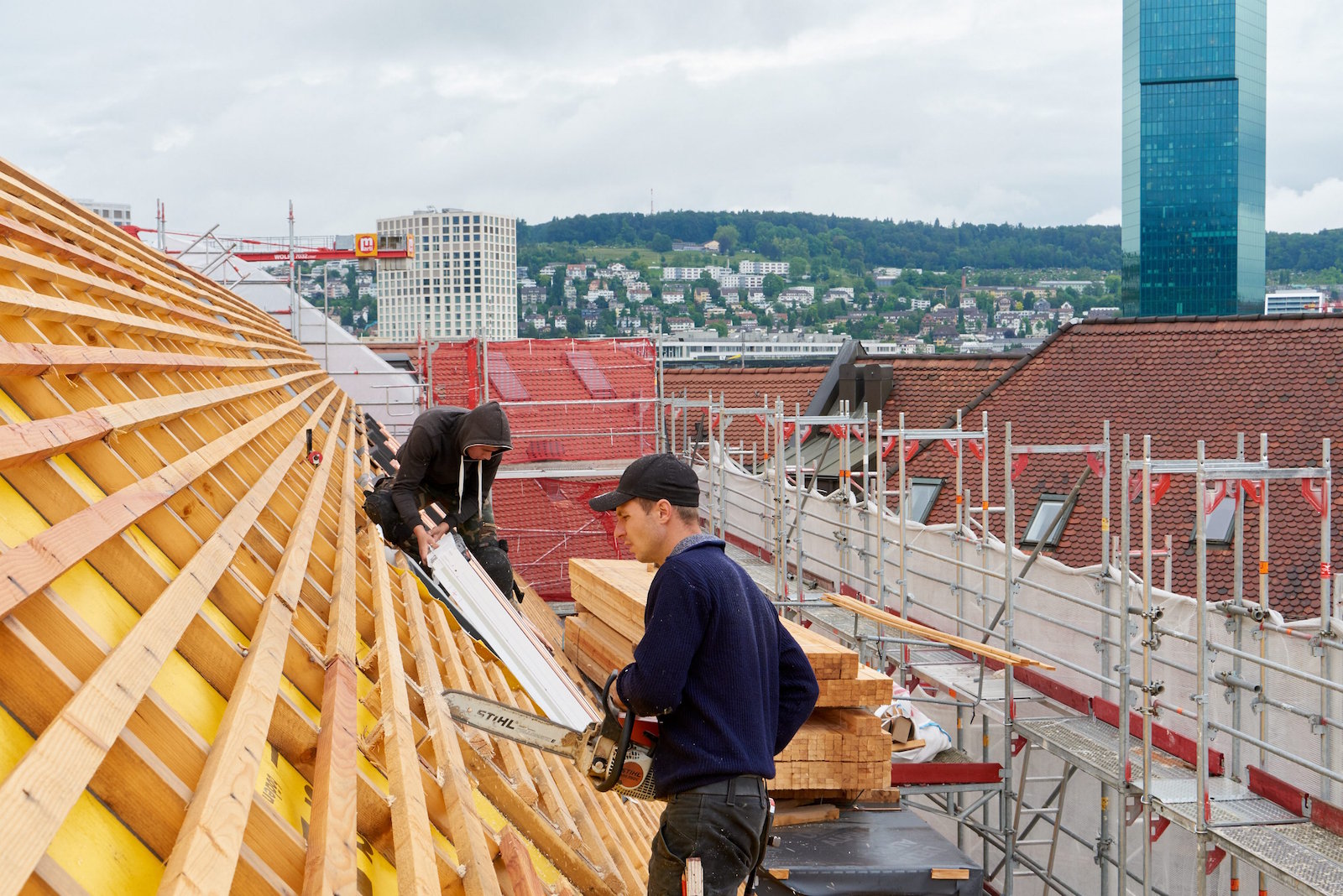 Zimmerleute über den Dächern von Zürich bei der Arbeit an einem Dachstuhl