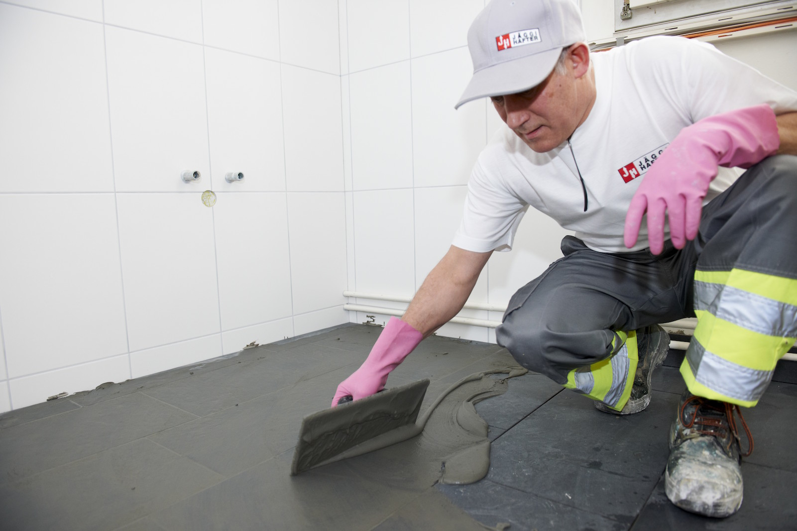 Handwerker beim Verfugen von Bodenfliesen