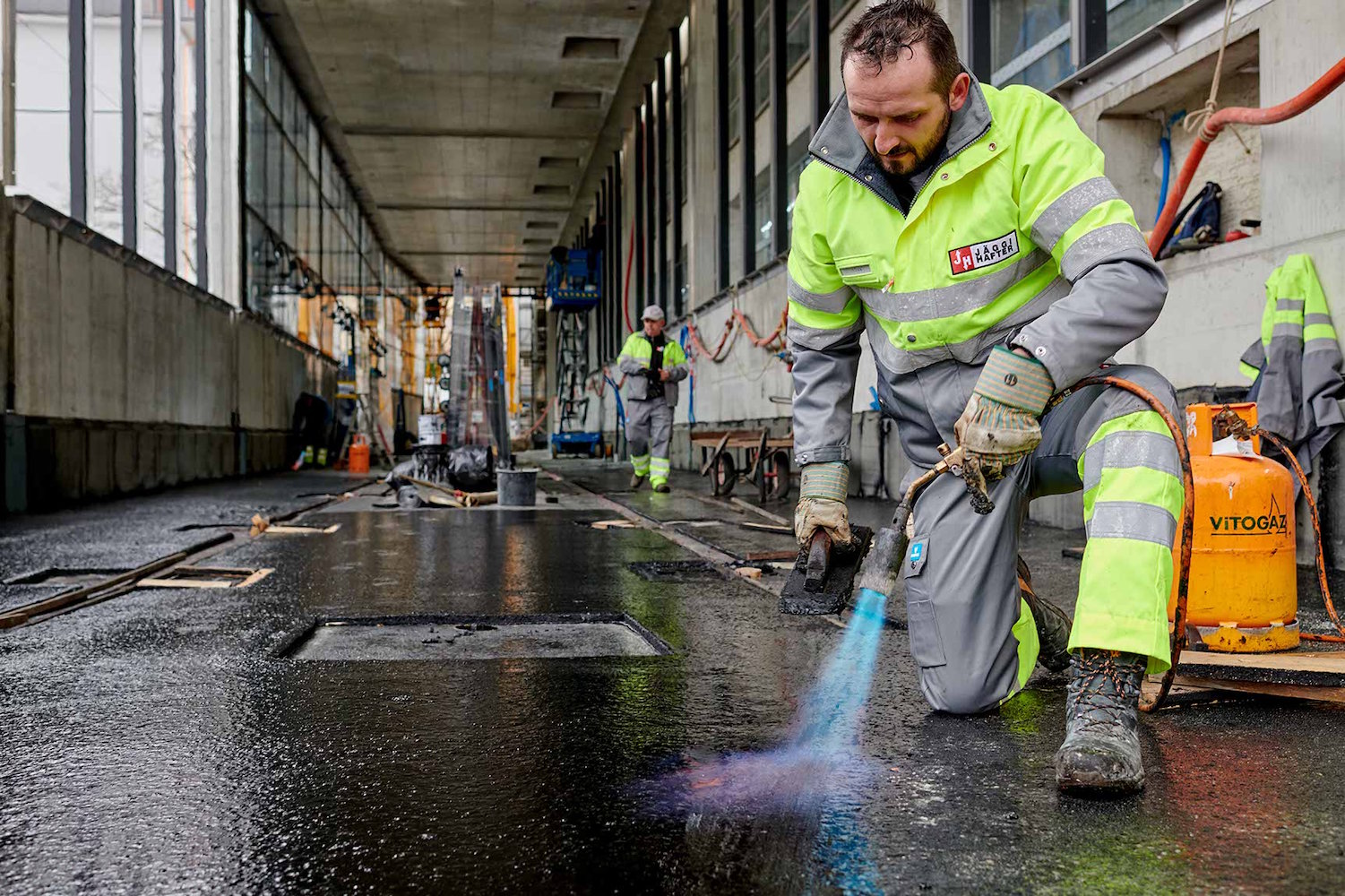 Mann kit Gasbrenner beim Erhitzen von Gussasphalt