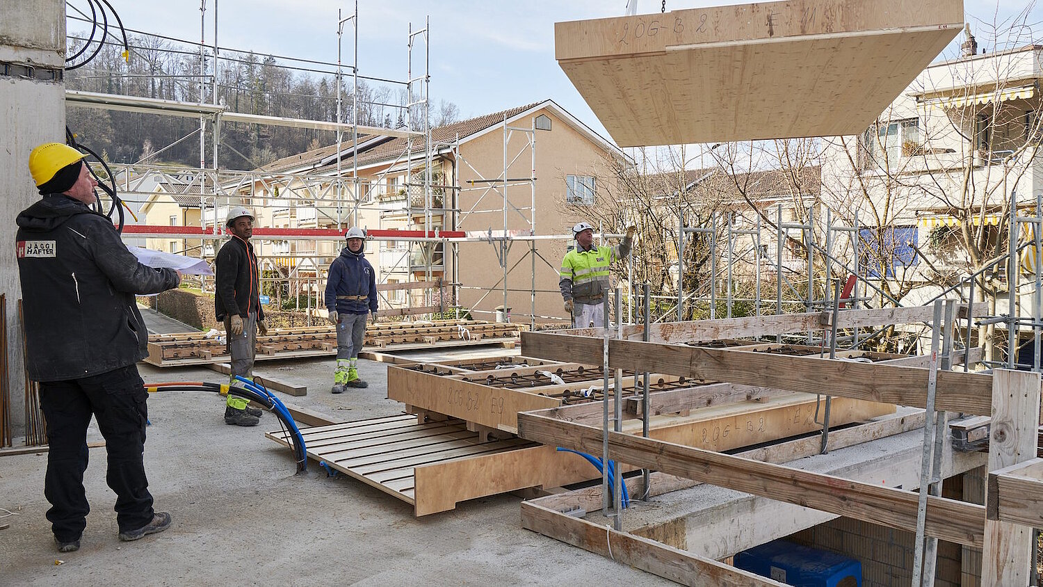 Bauarbeiter mit Modulwand am Kran